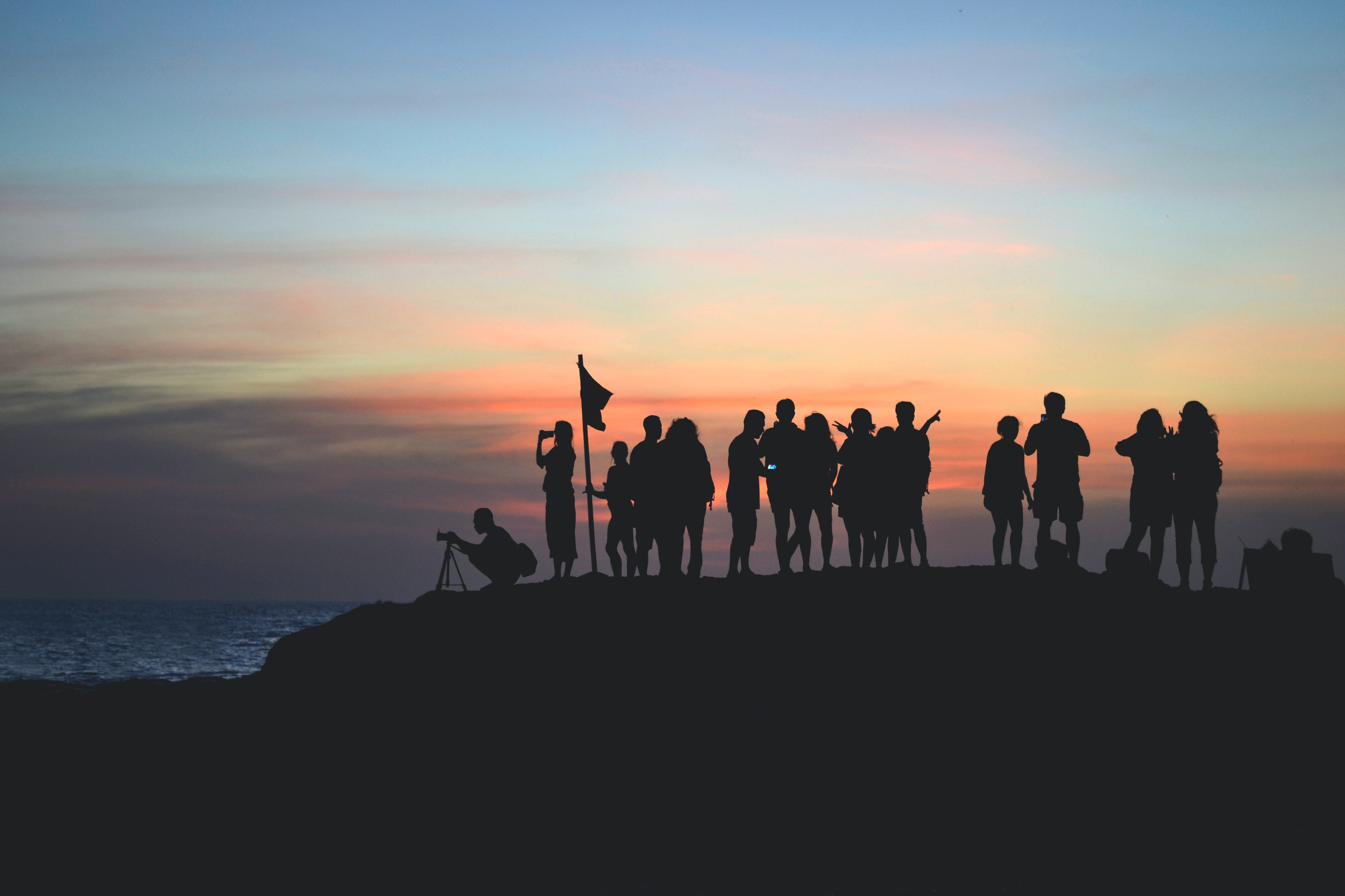 group of people standing on a hill silhouetted by the sunset