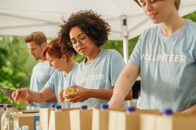 people standing under a tent packing food into paper bags