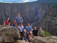 Nine students posing in front of a canyon.