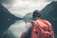 backpacker facing a body of water in the mountains