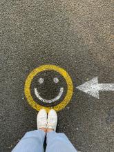 person in white shoes standing on happy face drawing on gray concrete road